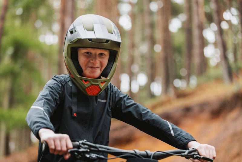 Person riding a bike in a forest wearing a helmet.