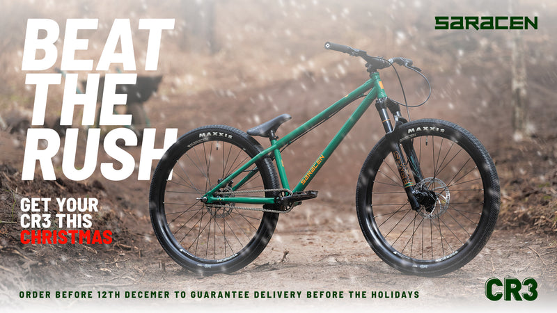 Green bicycle on a dirt road with promotional text and Saracen branding.