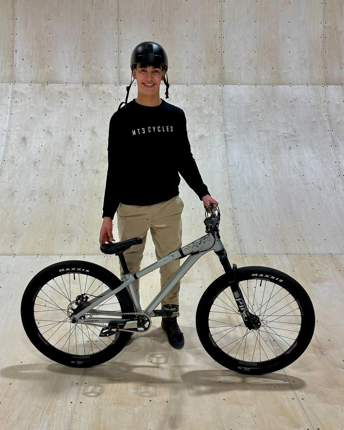 Person holding a bicycle in front of a concrete wall