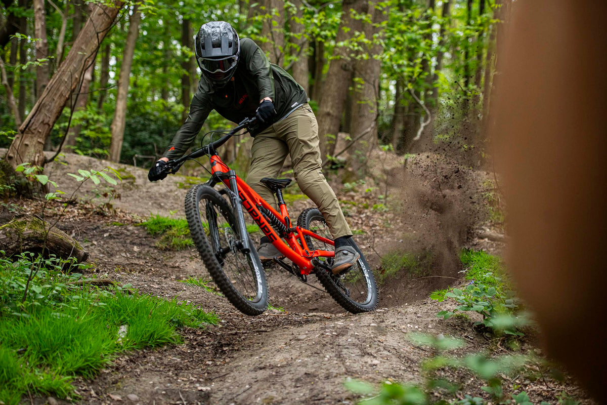 Person riding a red mountain bike through a forest trail