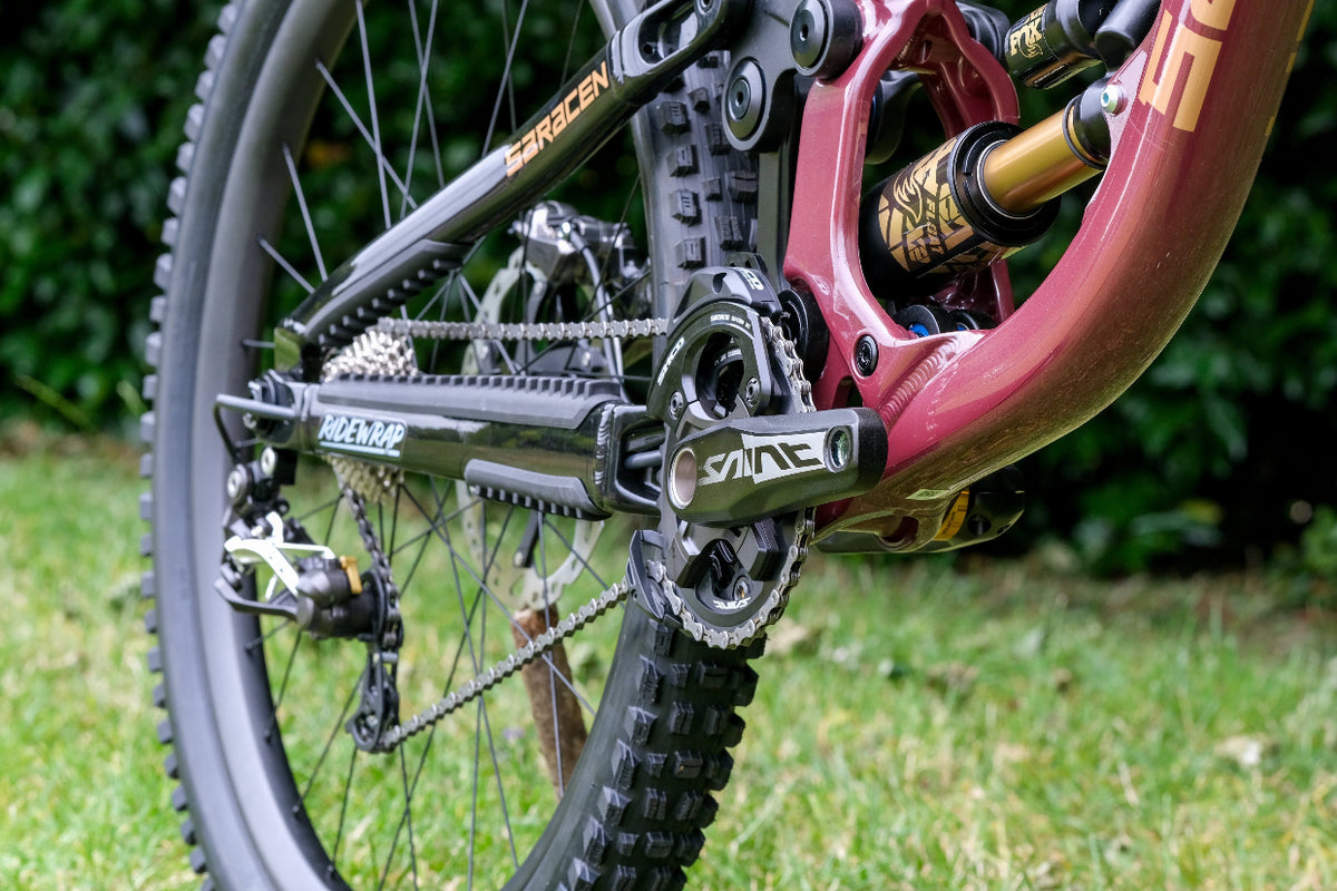 Close-up of a bicycle's chain and gear system with a blurred green background