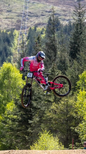 Biker in mid-air with a red bike against a forest background