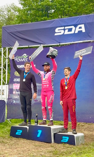 Three individuals standing on a podium with 'SDA' branding in the background