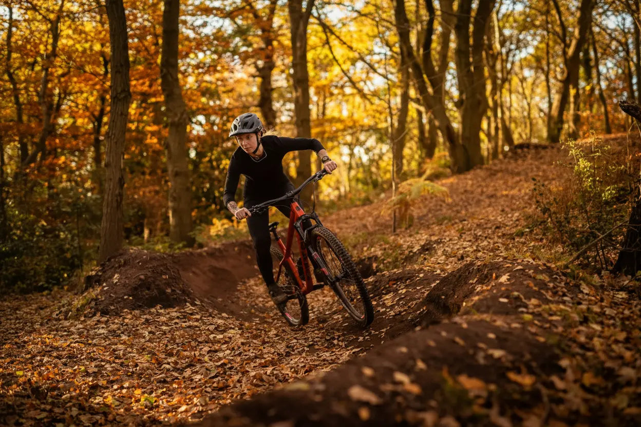 Person riding a mountain bike on a trail in an autumn forest