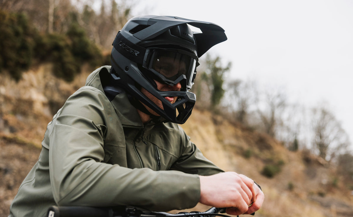 Person wearing a black helmet and green jacket on a bike in a natural setting
