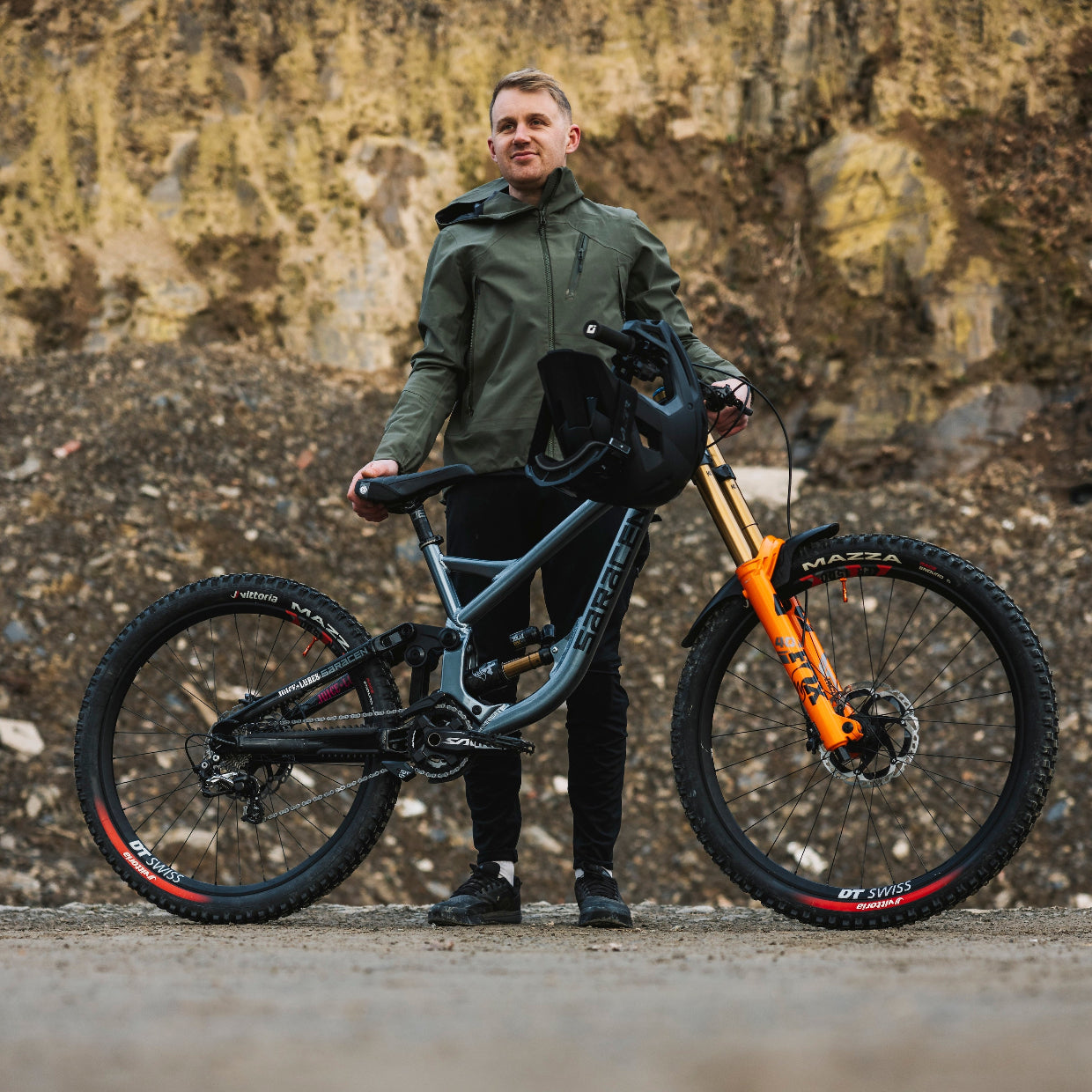 Man holding a mountain bike against a rocky background