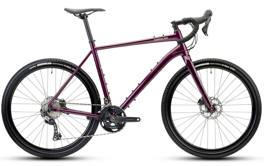 A purple and black gravel bicycle with drop handlebars, disc brakes, and knobby tires, shown from a side profile on a white background.