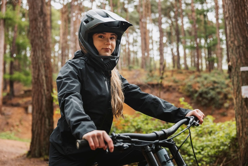 Person riding a bicycle in a forest wearing a helmet.
