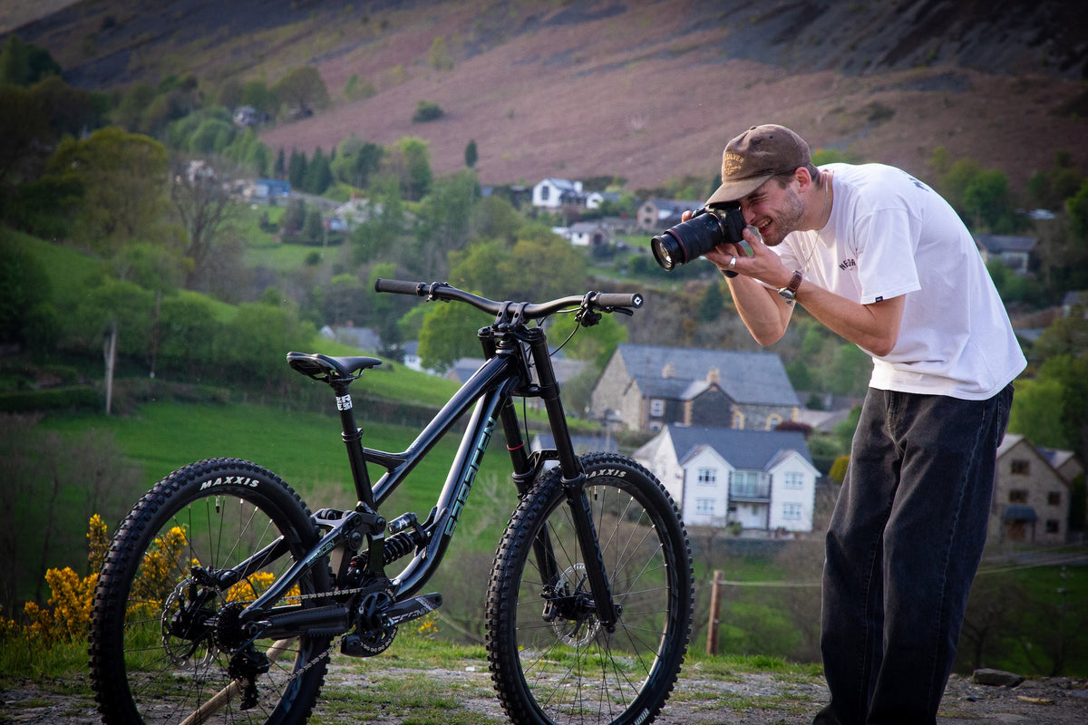 Man taking a photo of a mountain bike with a scenic background
