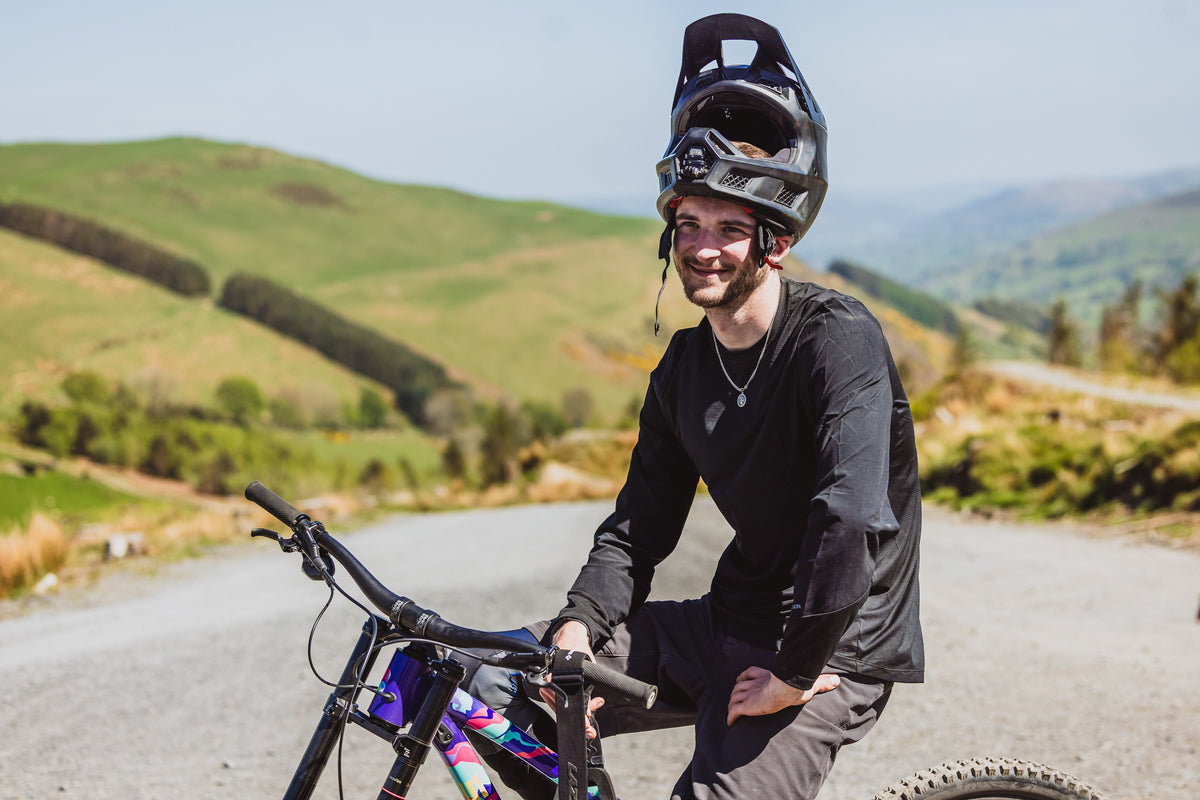Person with a mountain bike on a road with green hills in the background