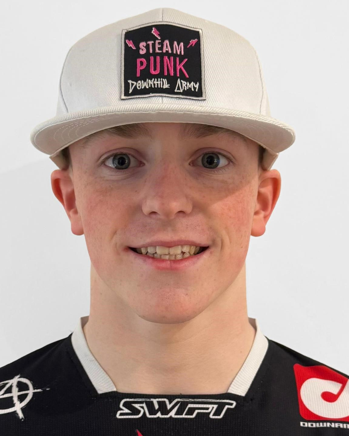 Person wearing a cap with 'Steam Punk' design and a black shirt with logos.