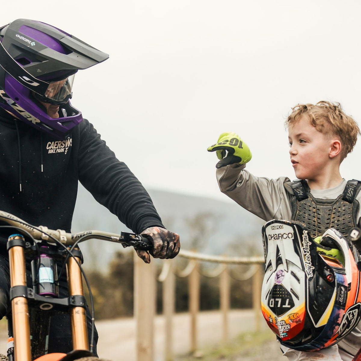 Person on a bike with a child wearing protective gear, both with helmets.