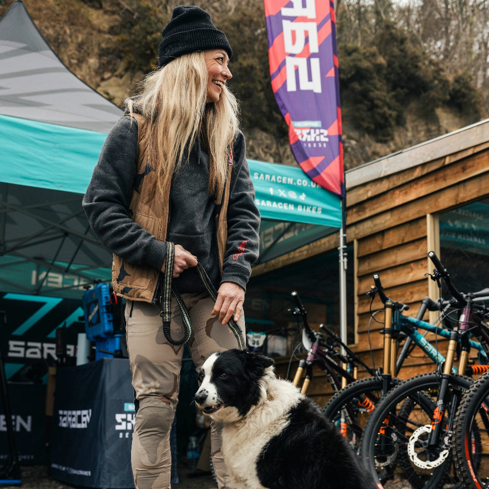 Person with a dog at an outdoor event with bikes and tents in the background