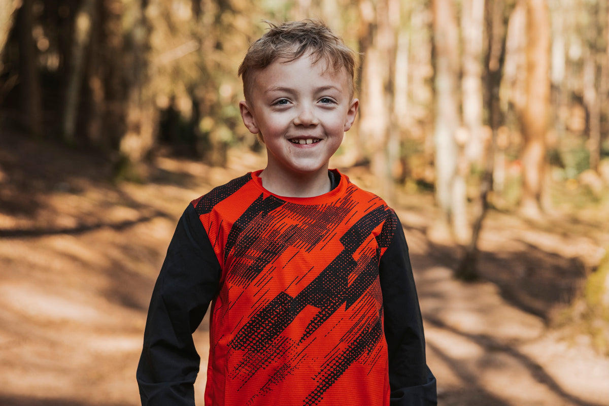 Child wearing a red and black shirt in a forest setting