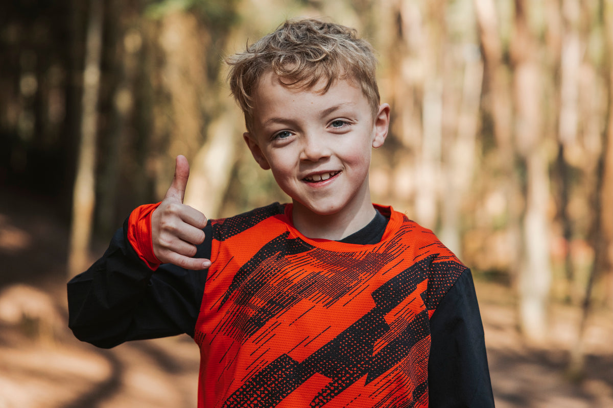 Child giving a thumbs up in a forest setting