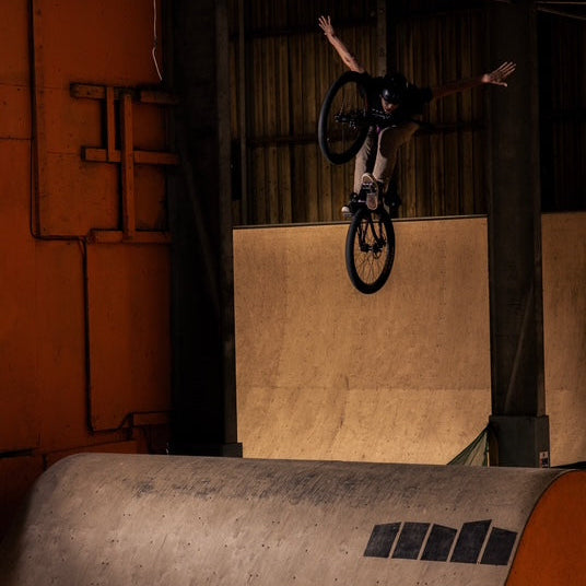 Person performing a bike trick on a ramp inside a building