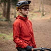 Person on a bike wearing a red jacket and helmet in a forest setting