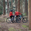 Two people on electric bikes in a forest setting