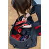Person organizing items in a black duffel bag on a brown surface