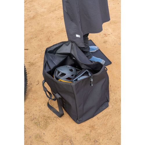 Black backpack with a helmet and clothing on a beige surface