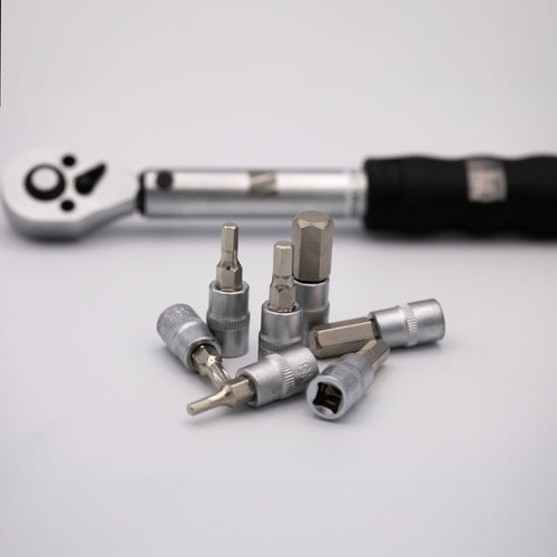 Set of ratchet wrench and drill bits on a light gray background