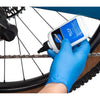 Person applying chain lube to a bicycle chain with a gloved hand