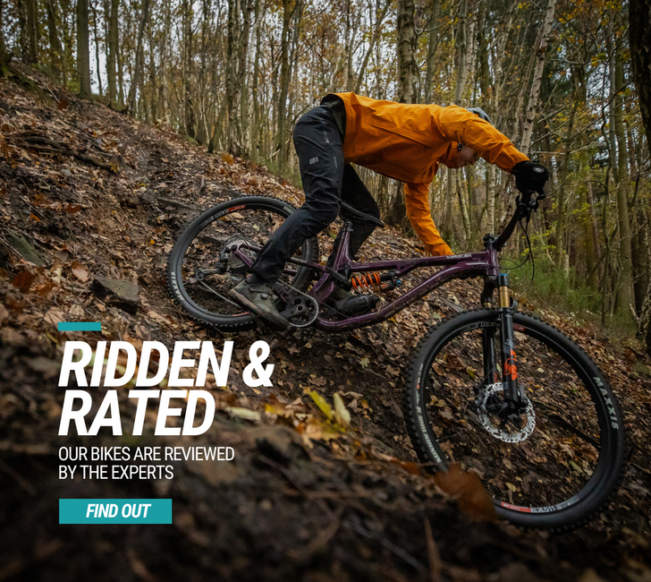 Person riding a mountain bike on a trail with text overlay about bike reviews.