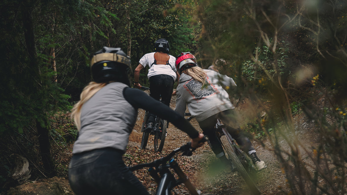 Three people riding bicycles through a forest